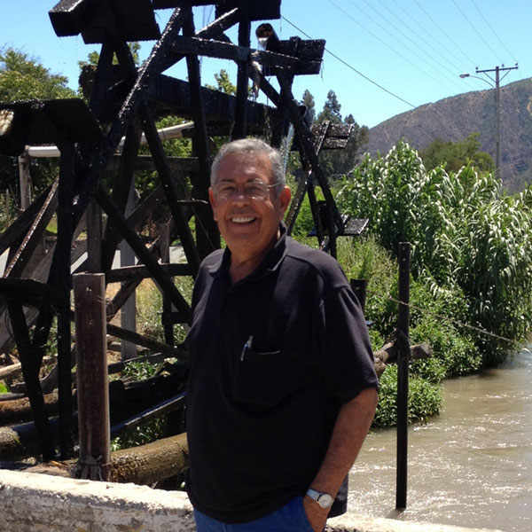 Jim Paiva posing near a water wheel